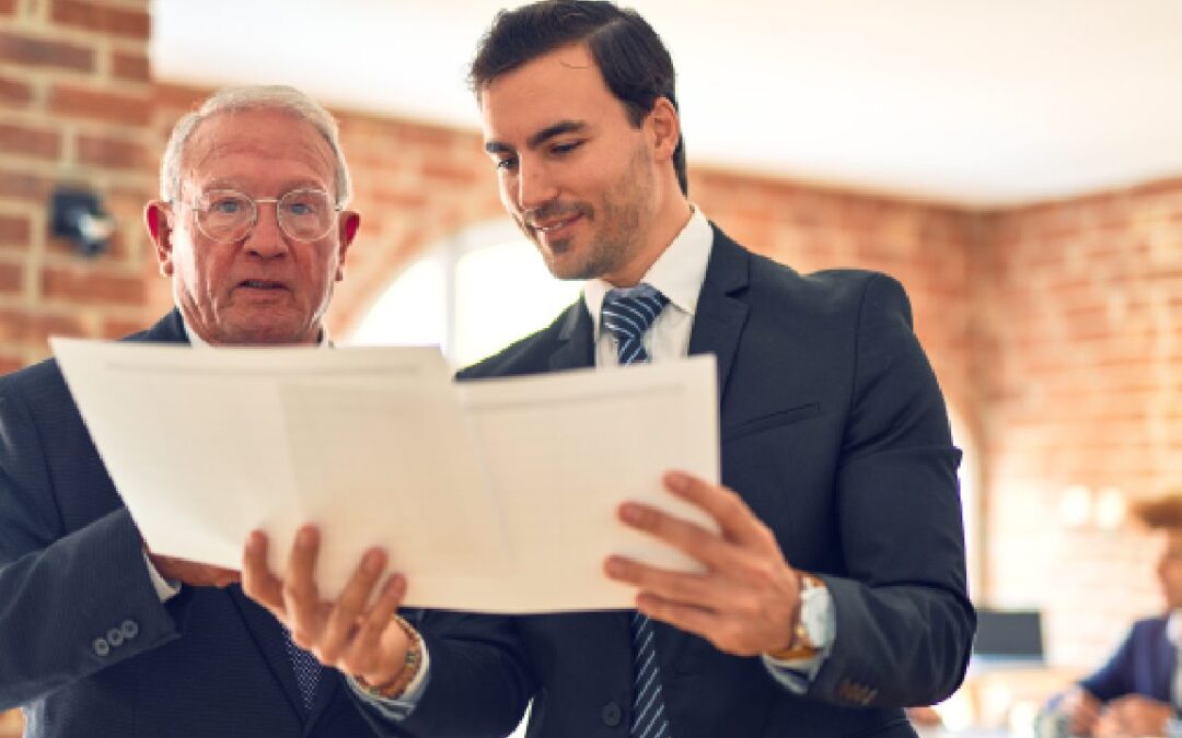 Two men in formal suits review a document together inside a brick-walled office, conveying a collaborative and professional atmosphere.